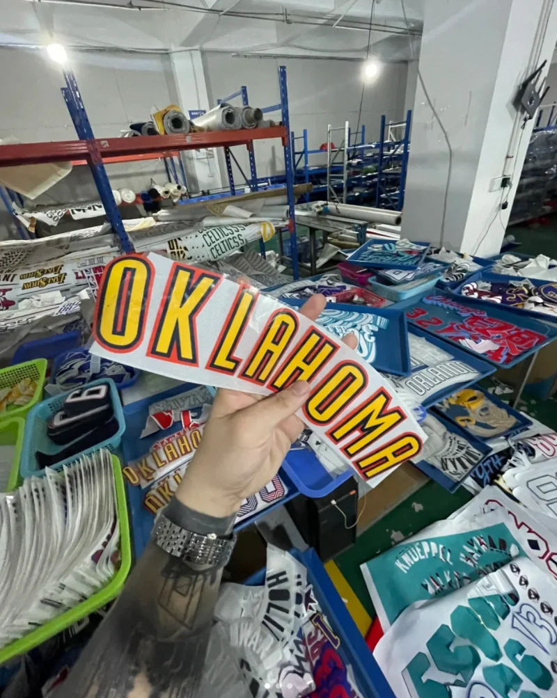 Hand holding yellow lettering with contrasting edges above trays of letter and number components