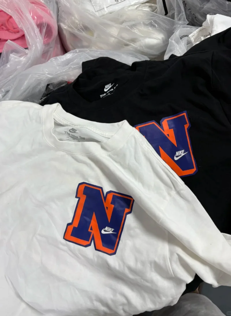 White and black T-shirts with a large blue letter outlined in orange on the chest