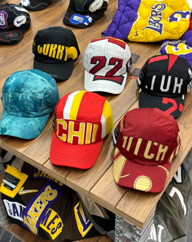 Sports caps in several colours with panels, lettering and numbers on a wooden table